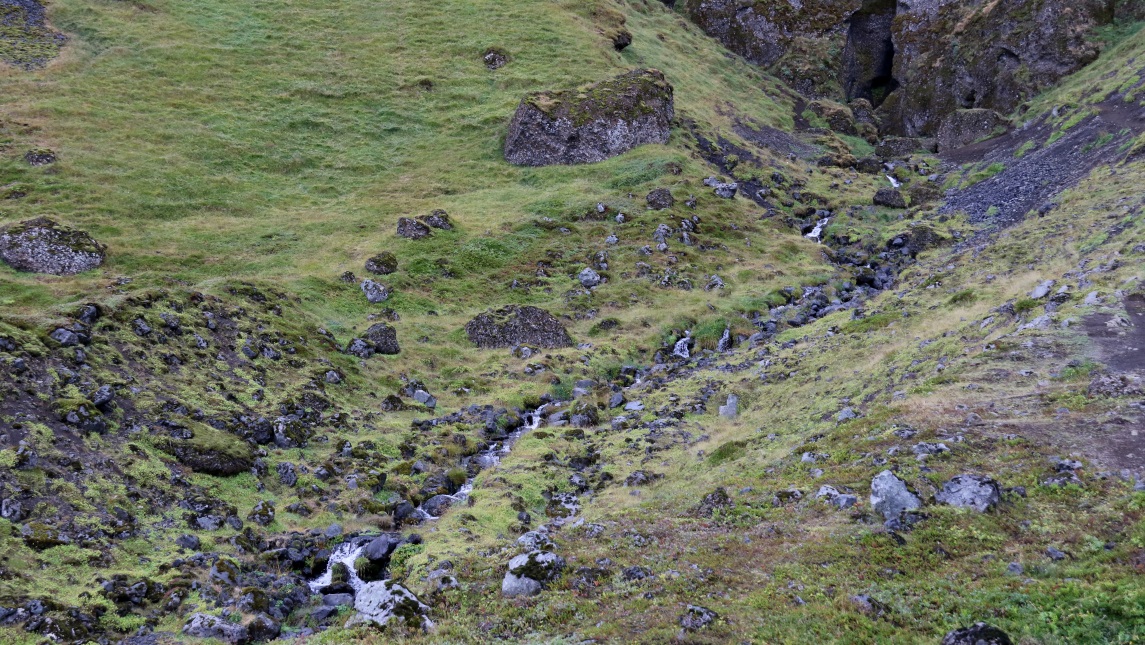 A small stream emerges from Raudfeldsgja Canyon